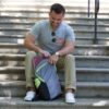 An individual sitting on cement stairs putting away a notebook into their eco friendly Chico Bag brand recycled plastics collapsible travel pack.