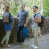 Three individuals talking outside to each other, each carrying an eco friendly Chico Bag brand recycled plastics collapsible travel pack.