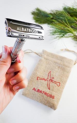 Albatross brand eco friendly plastic-free stainless steel flagship butterfly safety razor in hand with small sustainable Albatross burlap bag