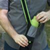 Close up view of environmentally friendly Limestone color Chico Bag brand bottle sling bag, that's made from recycled plastic bottles, being used outside by male.