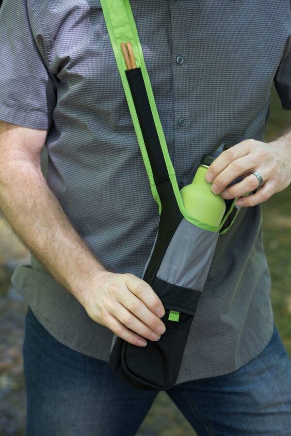 Close up view of environmentally friendly Limestone color Chico Bag brand bottle sling bag, that's made from recycled plastic bottles, being used outside by male.