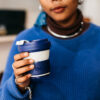 Woman holding blue pop-up, eco-friendly coffee cup from Pokito