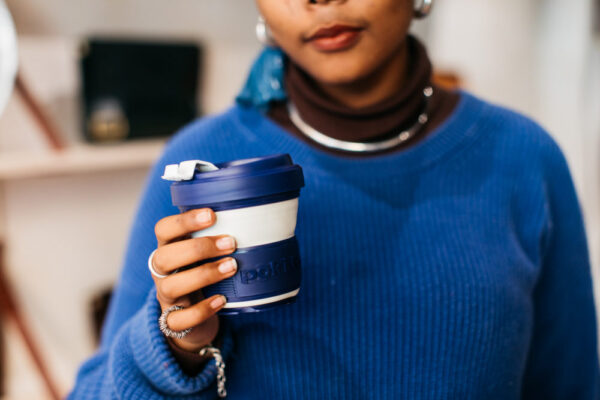 Woman holding blue pop-up, eco-friendly coffee cup from Pokito