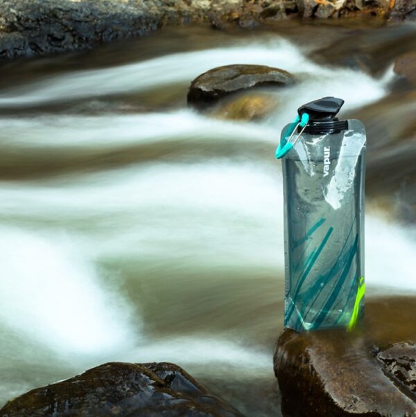 Reusable, collapsible roll-up water bottle bag by river for camping and hiking