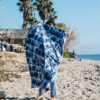 Person at beach unfolding Agua Blue eco-friendly, recycled festival blanket