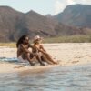 Couple at beach on eco-friendly, recycled Baja Aqua festival blanket for travel