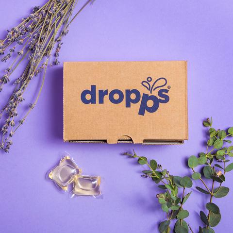 Dropps brand environmentally friendly mini unscented plant-based laundry pods next to Dropps labeled box with floral decorations.