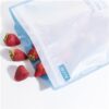 Strawberries spilling out of an open RussBe brand reusable gallon size bag in blue.