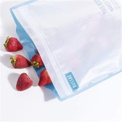 Strawberries spilling out of an open RussBe brand reusable gallon size bag in blue.