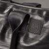 An Alchemy Goods large black shoulder tote made from upcycled bicycle inner tubes; AG logo shown in close-up