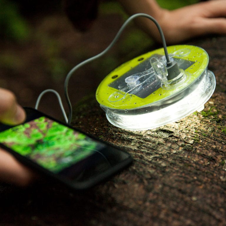 Sustainable Mpowerd brand Luci Pro Outdoor 2.0, inflatable solar power light used as a small light and portable charging station for iPhone out in nature.