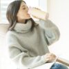 Eco friendly reusable Welly brand Original 12 oz rose colored mug being sipped by female with long brown hair in a comfy turtleneck sweater.