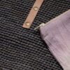 Close-up of blue raffia fibers, leather strap, and light purple removeable interior pocket with zipper closure