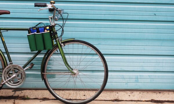 Side display of eco friendly Green Guru Gear brand Sixer 6-pack Top Tube Holder, loaded up with bottle brews, mounted on dark green bike.  Product is made from upcycled bicycle inner tubes, repurposed nylon fabric, and 18oz vinyl waterproof tarp.