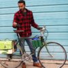 Male standing beside cruiser bike with eco friendly Green Guru Gear brand Sixer 6-pack Top Tube Holder, loaded up with bottle brews, mounted on bike frame.  Product is made from upcycled bicycle inner tubes, repurposed nylon fabric, and 18oz vinyl waterproof tarp.
