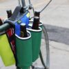 Point of view riding display of eco friendly Green Guru Gear brand Sixer 6-pack Top Tube Holder, loaded up with bottle brews, mounted on bike frame.  Product is made from upcycled bicycle inner tubes, repurposed nylon fabric, and 18oz vinyl waterproof tarp.
