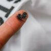 Zoomed in shot of finger tip covered in micro plastic fibers collected from eco friendly Guppyfriend brand Anti-Microplastic laundry bag.