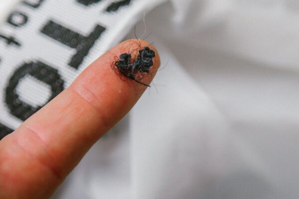 Zoomed in shot of finger tip covered in micro plastic fibers collected from eco friendly Guppyfriend brand Anti-Microplastic laundry bag.