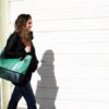 Woman using Alchemy Goods upcycled banner tote bag while on-the-go