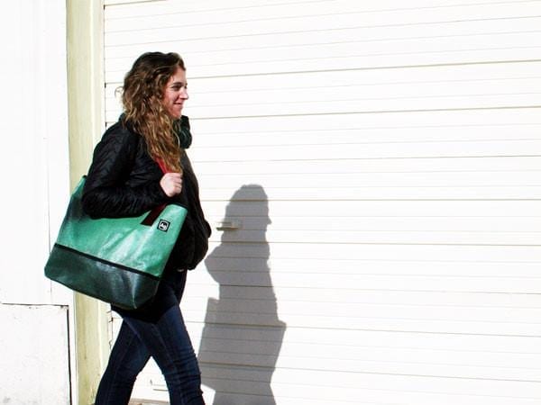 Woman using Alchemy Goods upcycled banner tote bag while on-the-go