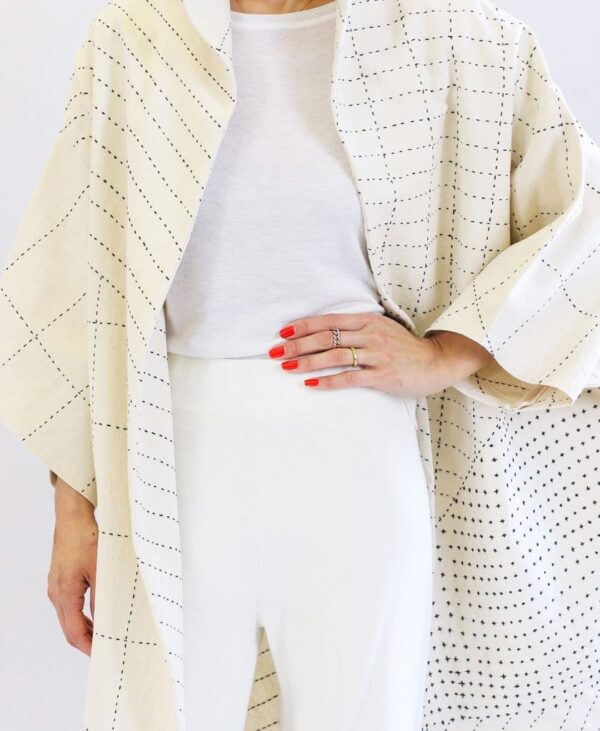 Close up of woman wearing a sustainable handmade long kimono canvas jacket in bone white made by Anchal brand.