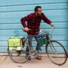 Male getting ready to ride away on his bike loaded up with the multi colored upcycled Double Dutch Pannier on rear wheel rack made by eco friendly Green Guru brand.