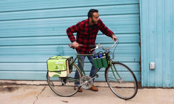 Male getting ready to ride away on his bike loaded up with the multi colored upcycled Double Dutch Pannier on rear wheel rack made by eco friendly Green Guru brand.