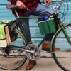 Close up shot of male getting ready to ride away on his bike loaded up with the multi colored upcycled Double Dutch Pannier on rear wheel rack made by eco friendly Green Guru brand.