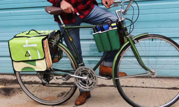 Close up shot of male getting ready to ride away on his bike loaded up with the multi colored upcycled Double Dutch Pannier on rear wheel rack made by eco friendly Green Guru brand.