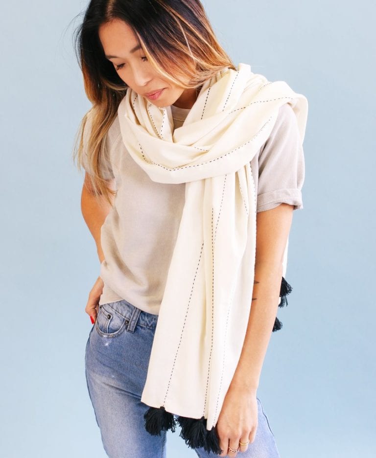 Earth friendly Anchal brand bone white Didi scarf handmade with sustainable 100% organic cotton, worn loosely wrapped around the neck of female model.