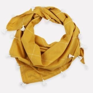 Close up photo of, loosely tied, eco friendly gold grid organic cotton square scarf with white tassels, made by Anchal brand.