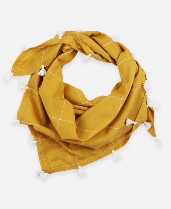 Close up photo of, loosely tied, eco friendly gold grid organic cotton square scarf with white tassels, made by Anchal brand.