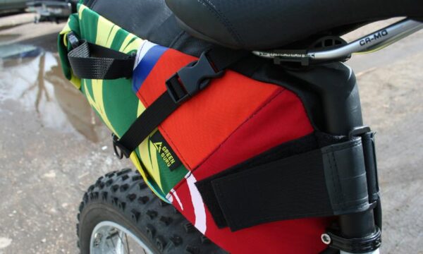 Close up photo of multicolor upcycled fabric Green Guru Gear brand Haluer Seat Bag Bike Pack displayed on white fat-tire bike with black seat.