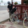 Male removing High Roller 36 liter backpack convertible pannier from rear wheel rack and transition into a backpack.  Pack is made with inner tubes and other upcycled materials by earth friendly Green Guru Gear brand.