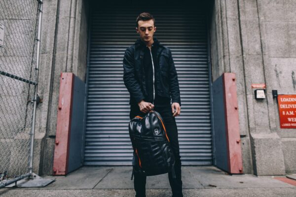 Male posing with the Alchemy Goods Brooklyn backpack made from upcycled inner tubes.