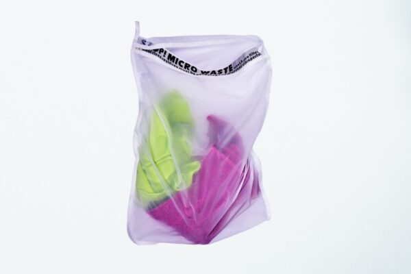 Earth friendly Guppyfriend brand anti-microplastic laundry bag with clothing inside.