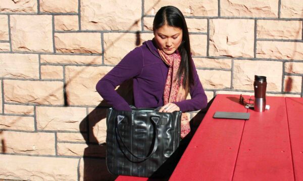 Woman using her vegan Alchemy Goods tote bag made from upcycled bicycle inner tubes