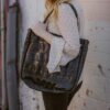 Model posing with Alchemy Goods large black shoulder tote made from upcycled bicycle inner tubes.