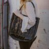 Model posing with Alchemy Goods large black shoulder tote made from upcycled bicycle inner tubes.