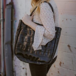 Model posing with Alchemy Goods large black shoulder tote made from upcycled bicycle inner tubes.