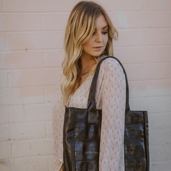 Model posing with Alchemy Goods large black shoulder tote made from upcycled bicycle inner tubes.