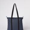 Back of Ten Tree brand daily tote bag shown in dark blue fabric with black strap