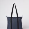 Back of Ten Tree brand daily tote bag shown in dark blue fabric with black strap