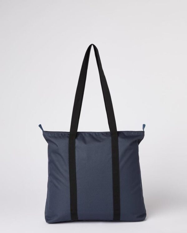 Back of Ten Tree brand daily tote bag shown in dark blue fabric with black strap