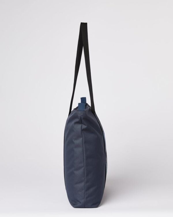Side profile of the Ten Tree brand daily tote bag in dark blue with a waves print; made with REPREVE fabric and BLOOM foam padding