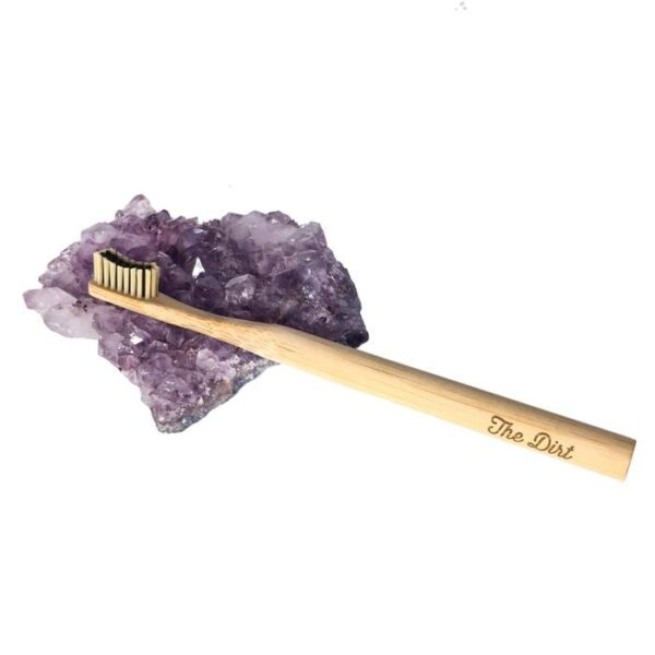 The Dirt brand eco friendly Bamboo Toothbrush on a decorative geode.