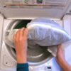 Filling up a white top load washing machine with eco friendly Guppyfriend brand anti-micro plastic laundry bag.