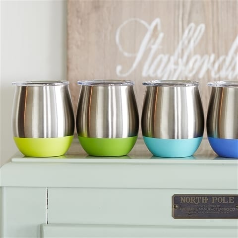 Four different colored sustainable U-Konserve brand insulated stainless drink tumblers with lids displayed on white entry table.  The colors include from left to right: Yellow, lime, turquoise, and marine blue.