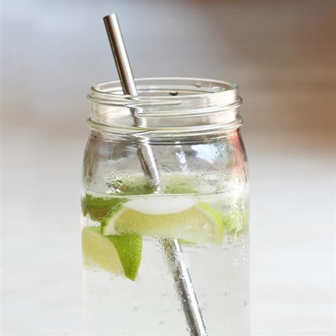 U-Konserve brand stainless steel straw being used to sip lemon lime water from glass mason jar.