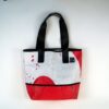 Large tote bag made of upcycled advertising banners from Alchemy Goods; shown with red and white print